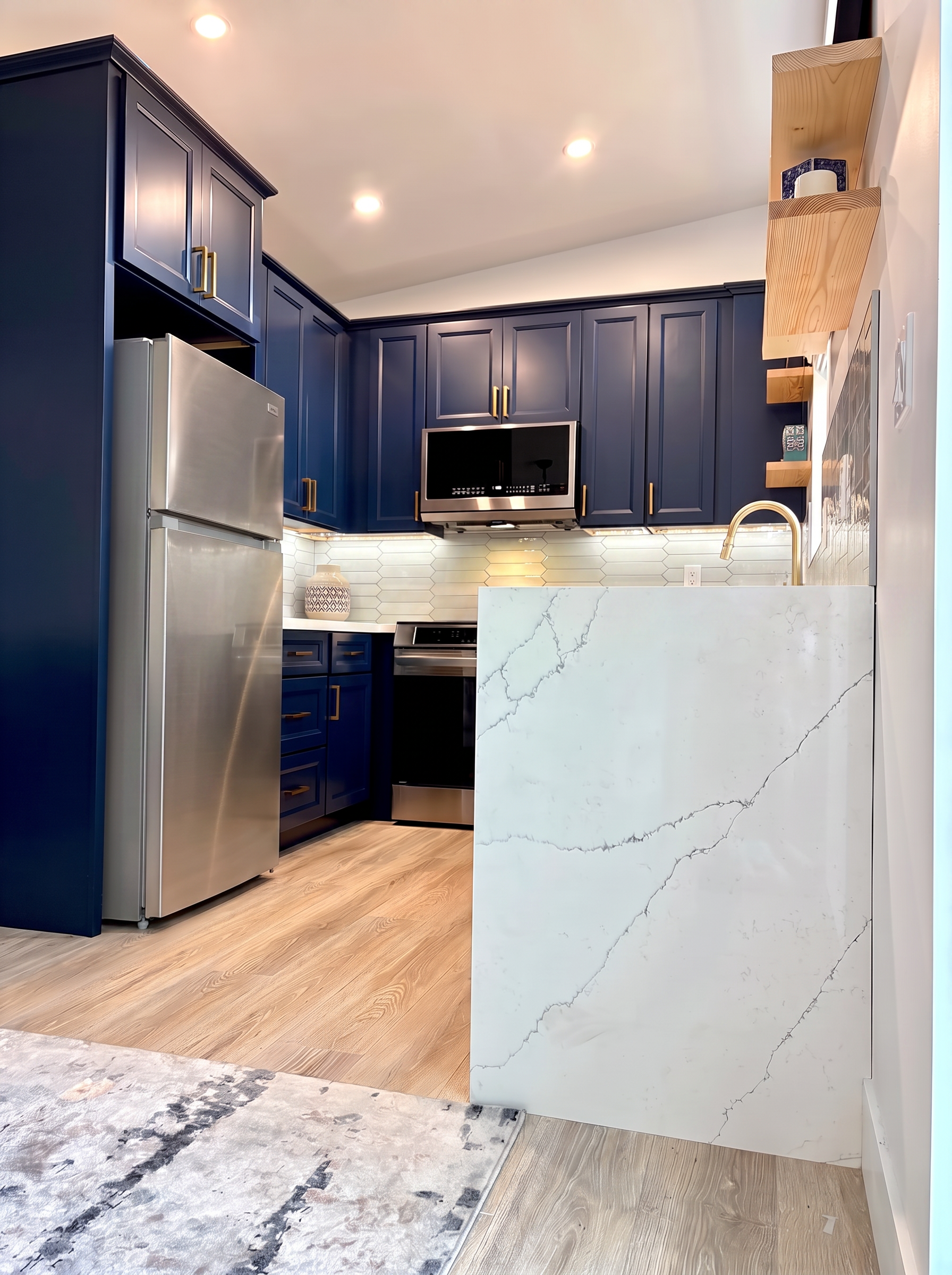 ADU kitchen viewed from the living area, showing the waterfall quartz peninsula and navy cabinetry