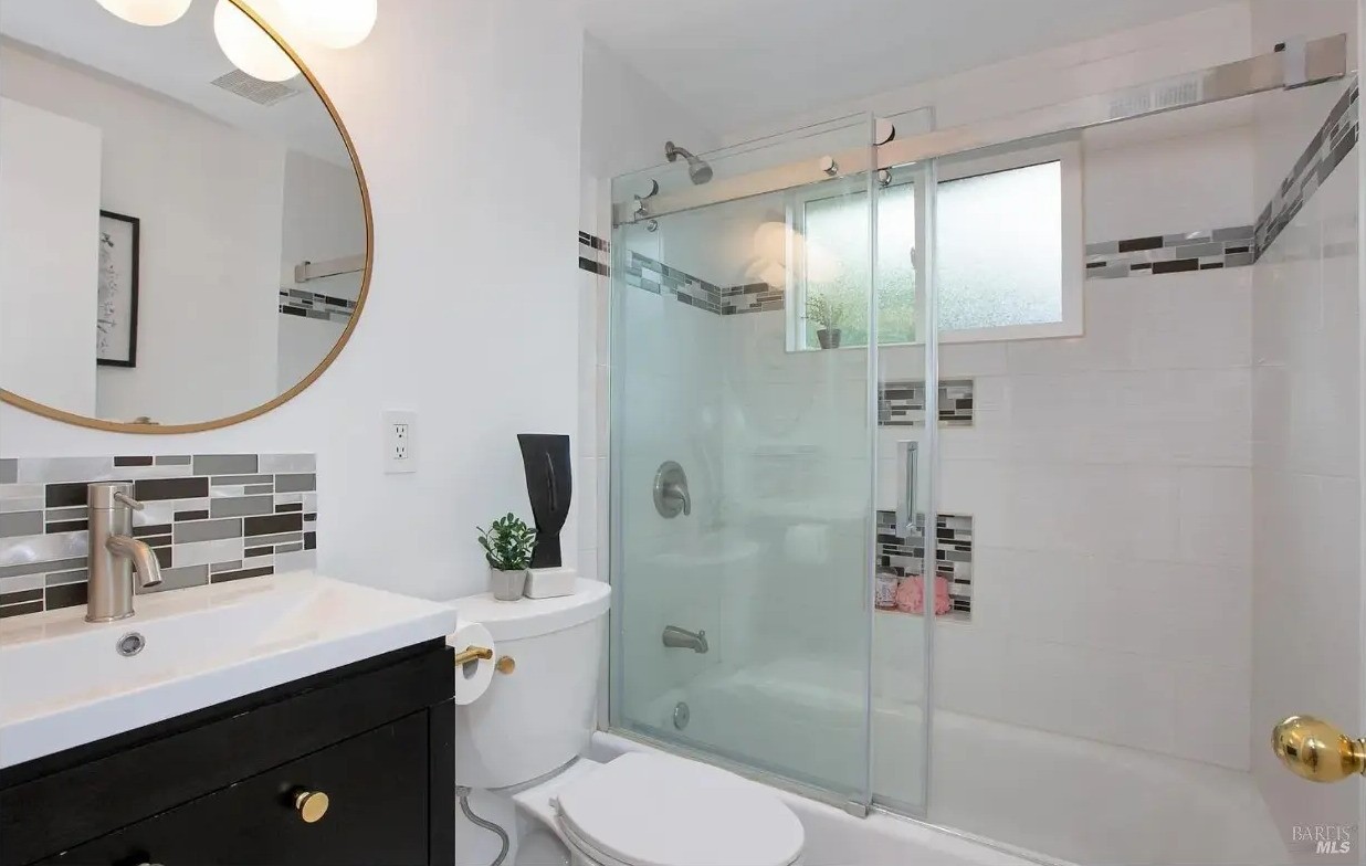 Bathroom with shower over tub and round mirror