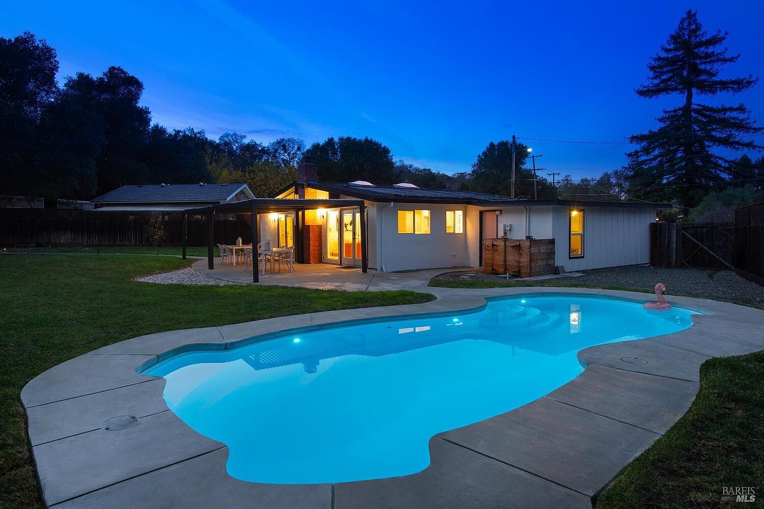 The mid-century swimming pool at 970 Glenwood Drive glowing at dusk beneath the oaks